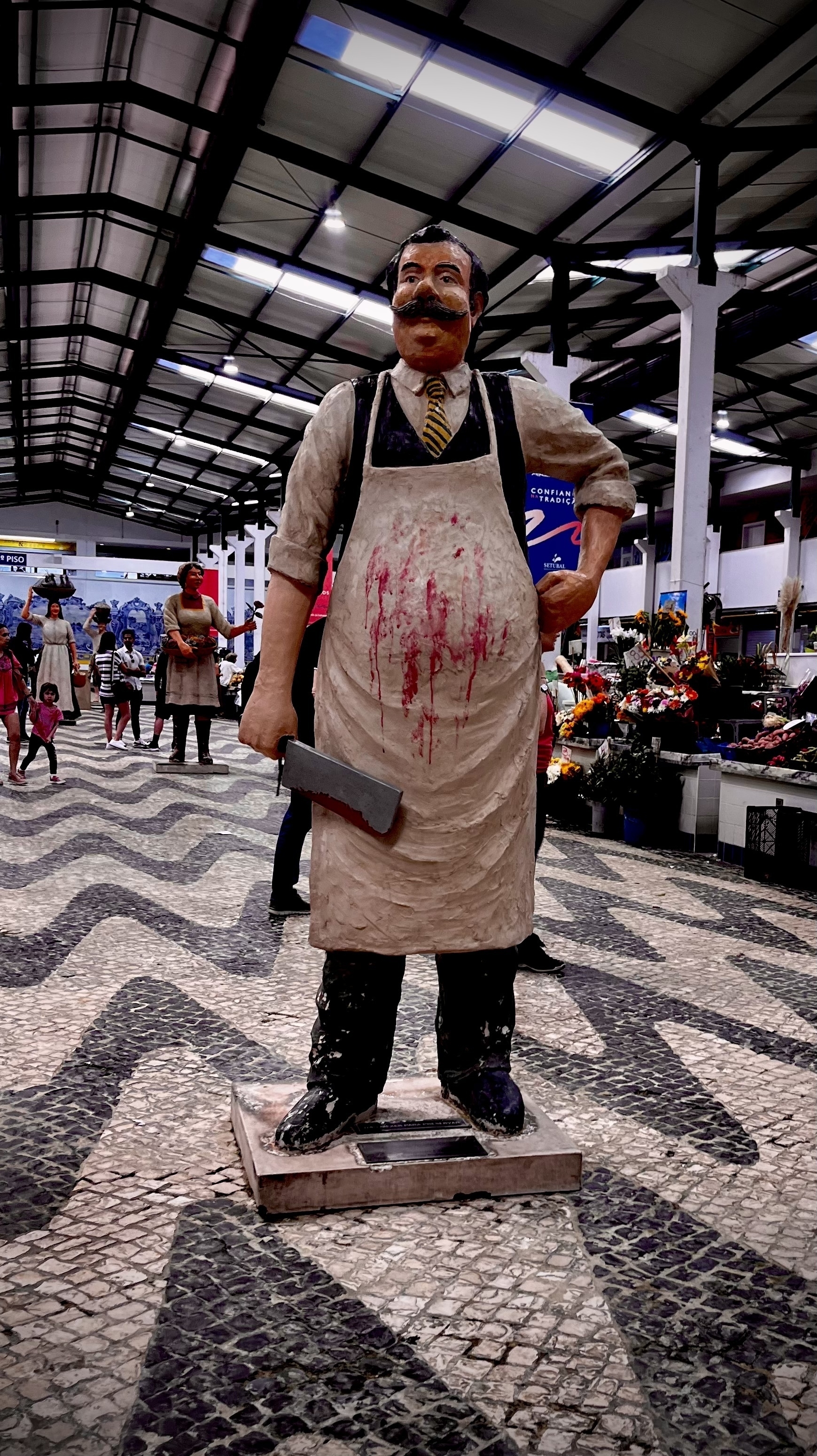Big model of a butcher, with a bloodied clever and apron, at Setúbal market