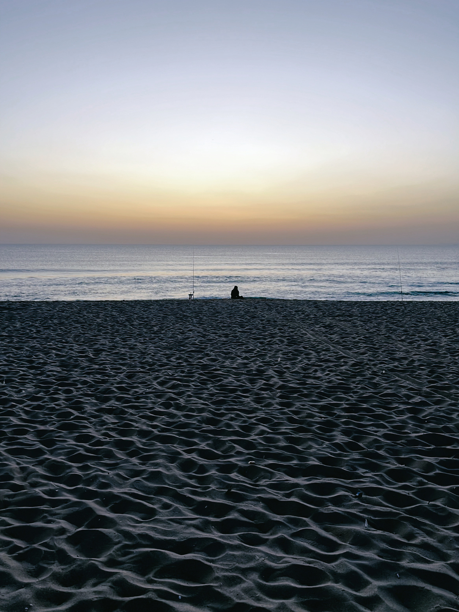 A lone fisherman on the beach in Comporta, Portugal, at sunset