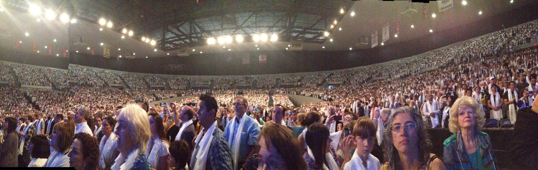 The audience of a large arena welcoming His Holiness the Dalai Lama to Portland. Everyone has Khatags, white silk scarves, around their necks, a traditional Tibetan greeting