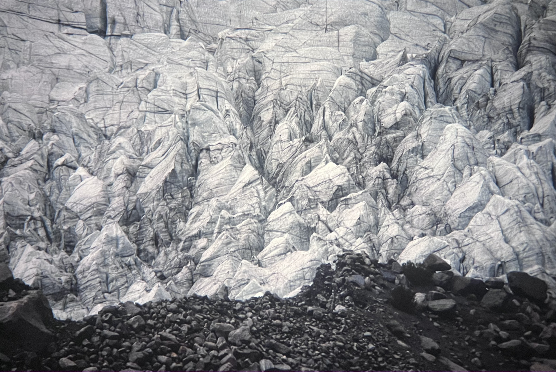 The terminus of the Batura Glacier in Pakistan showing a wall of ice with rocks and boulders in the foreground.