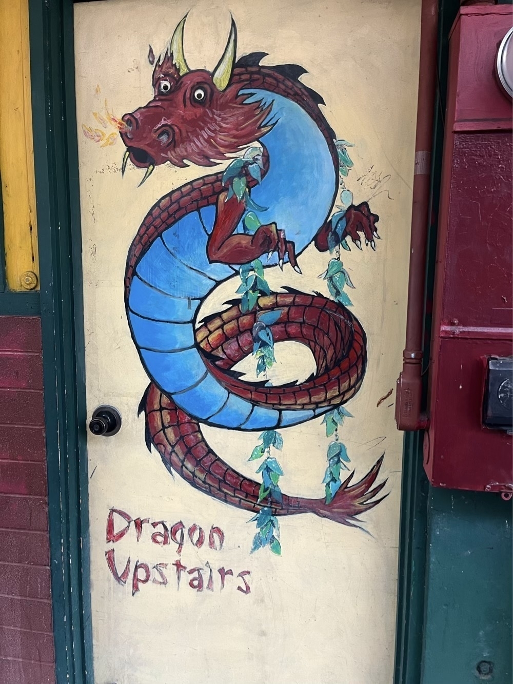 Drawing of a blue and red Dragon on a door with the words, Dragon Upstairs