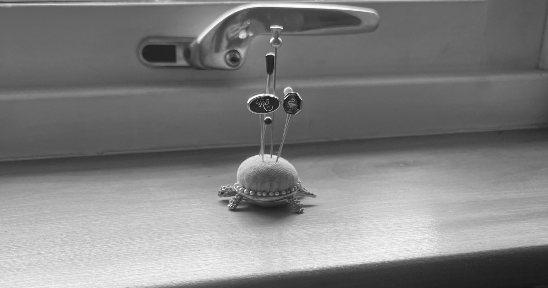 A black and white photo of a small, tortoise shaped pin cushion
