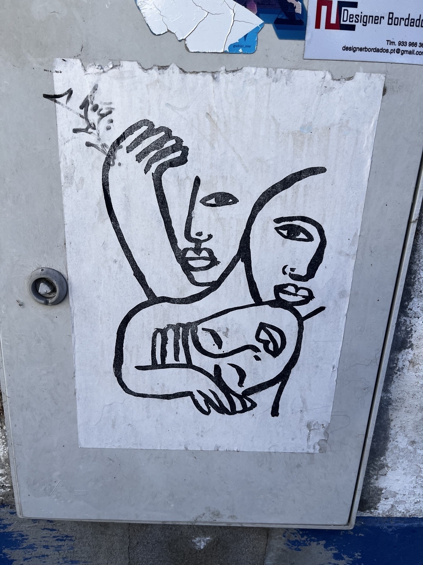 A small street drawing showing three faces intertwined with some eyes closed and some shut